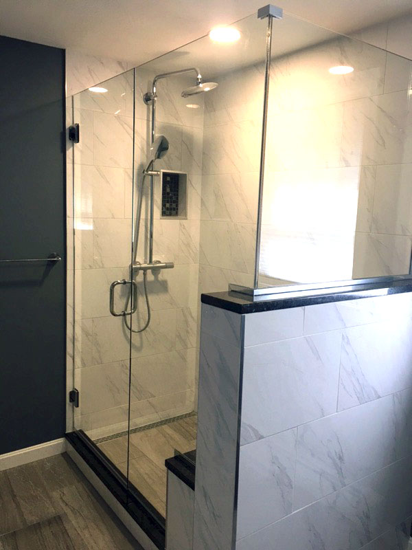 Custom tiled shower with Linear Drain to accommodate large format tile. 12 x 24 Carrara Wall Tile, with Linden Point Grigio Floor tile on main bath and in shower. Threshold, Seat Bench, and 1/2 wall cap are Blue Pearl, custom Granite.